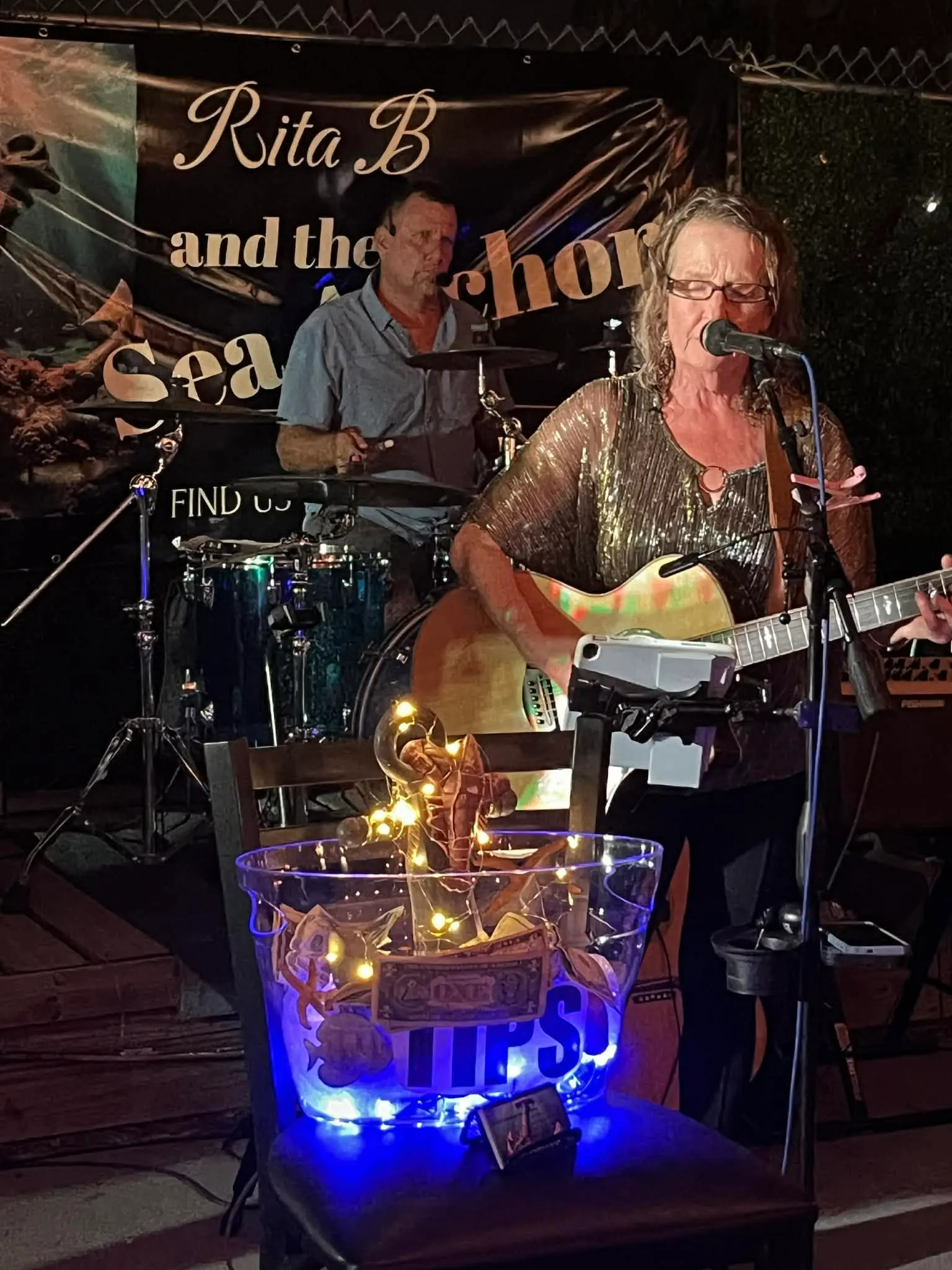Rita B performing at night beside a glowing tips bucket