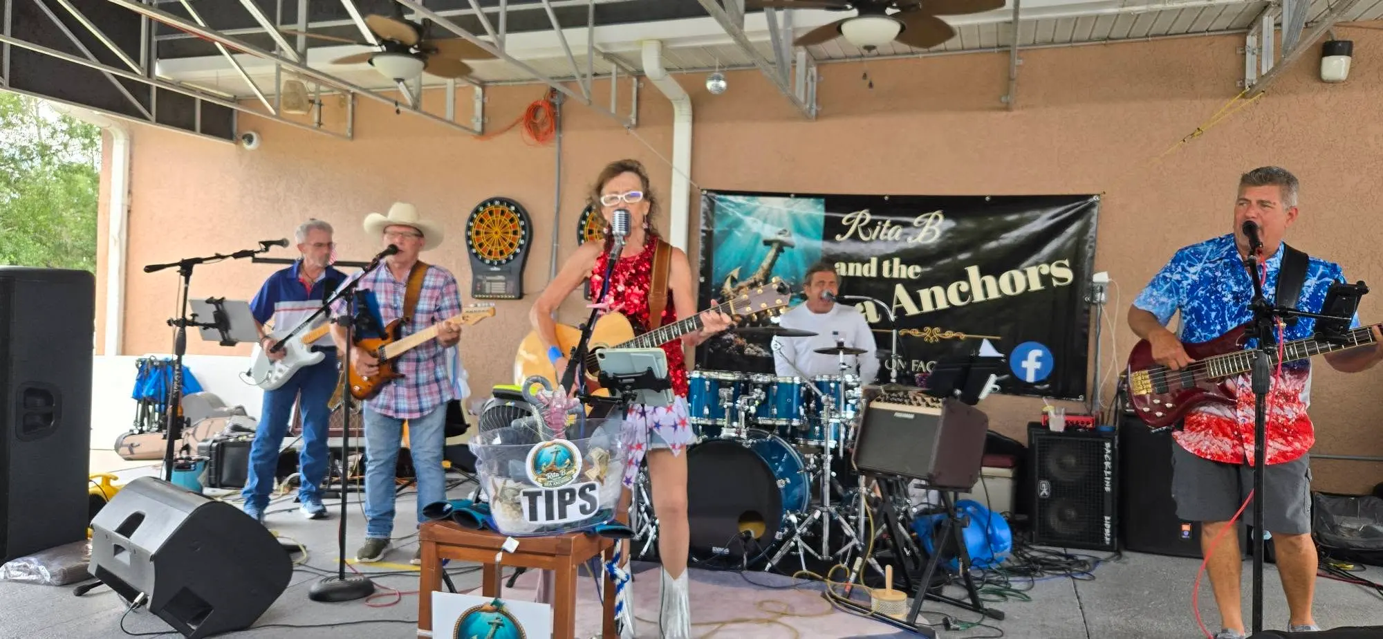 The Rita B Band spread across a covered patio stage under the band banner